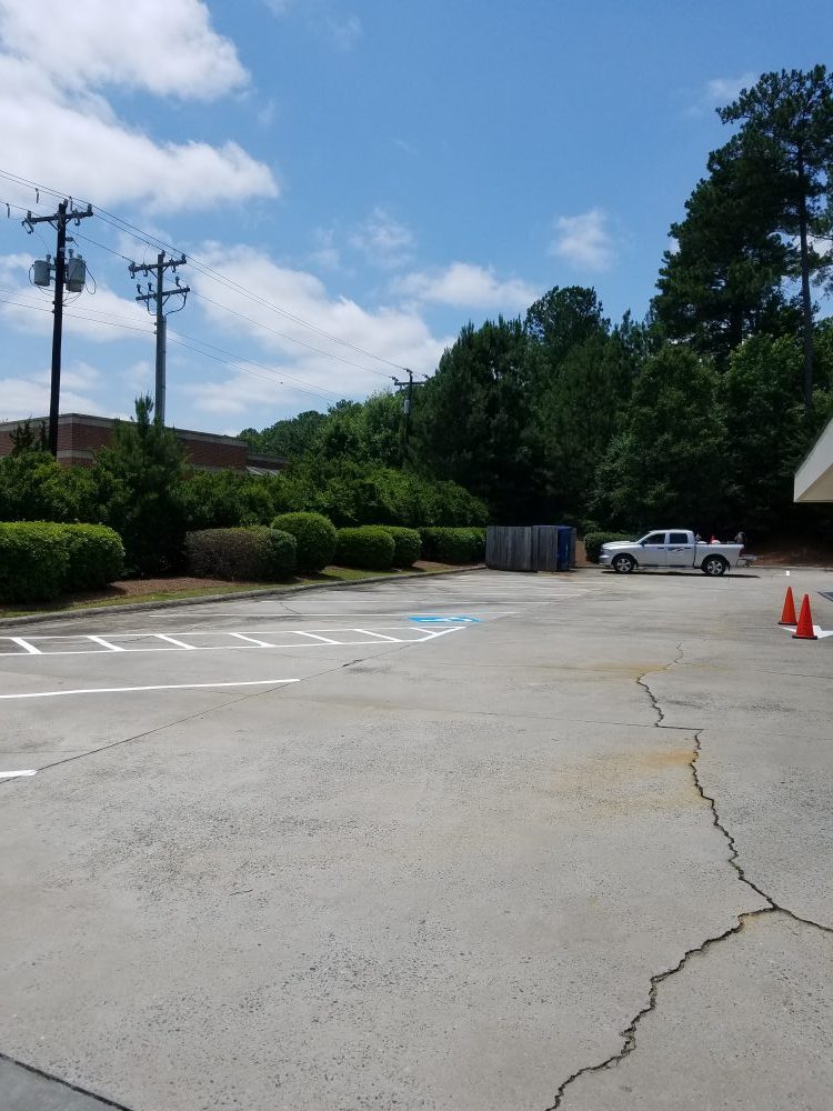 parking lot with large cracks in need of repair, repaving