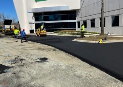 SMI Paving crew and roller paving beside an office building