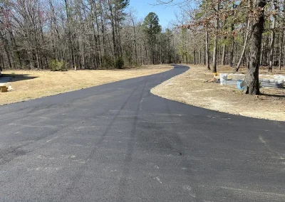 New residential asphalt driveway bordered by trees
