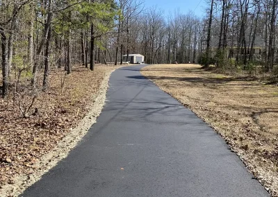 Long new asphalt driveway through a wooded lot