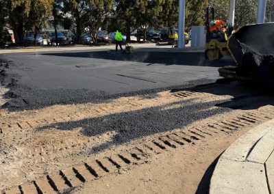 Asphalt paving crew resurfacing a gas station lot